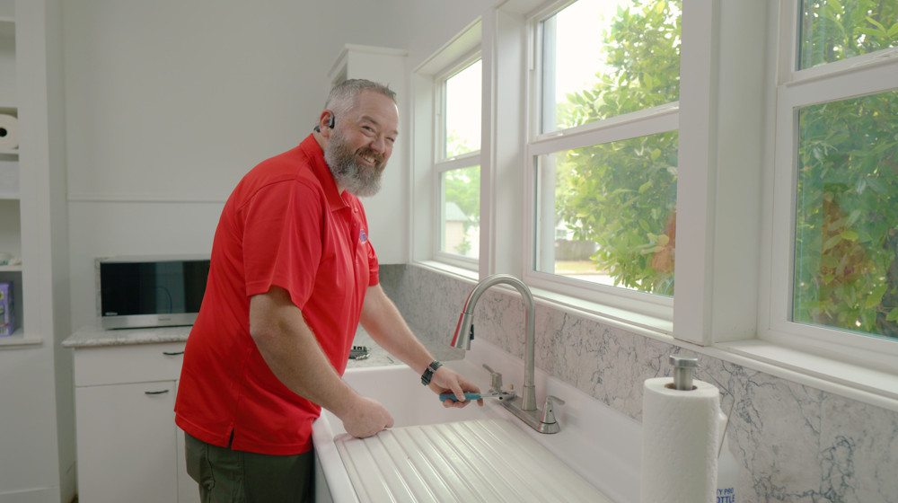A plumber working on a kitchen faucet