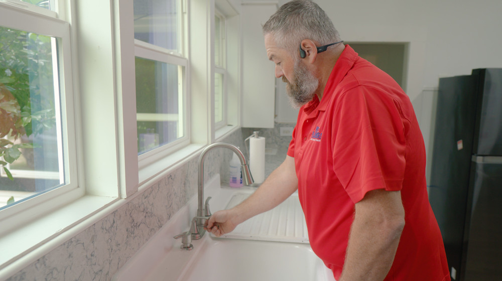 A plumber testing the water at a kitchen faucet