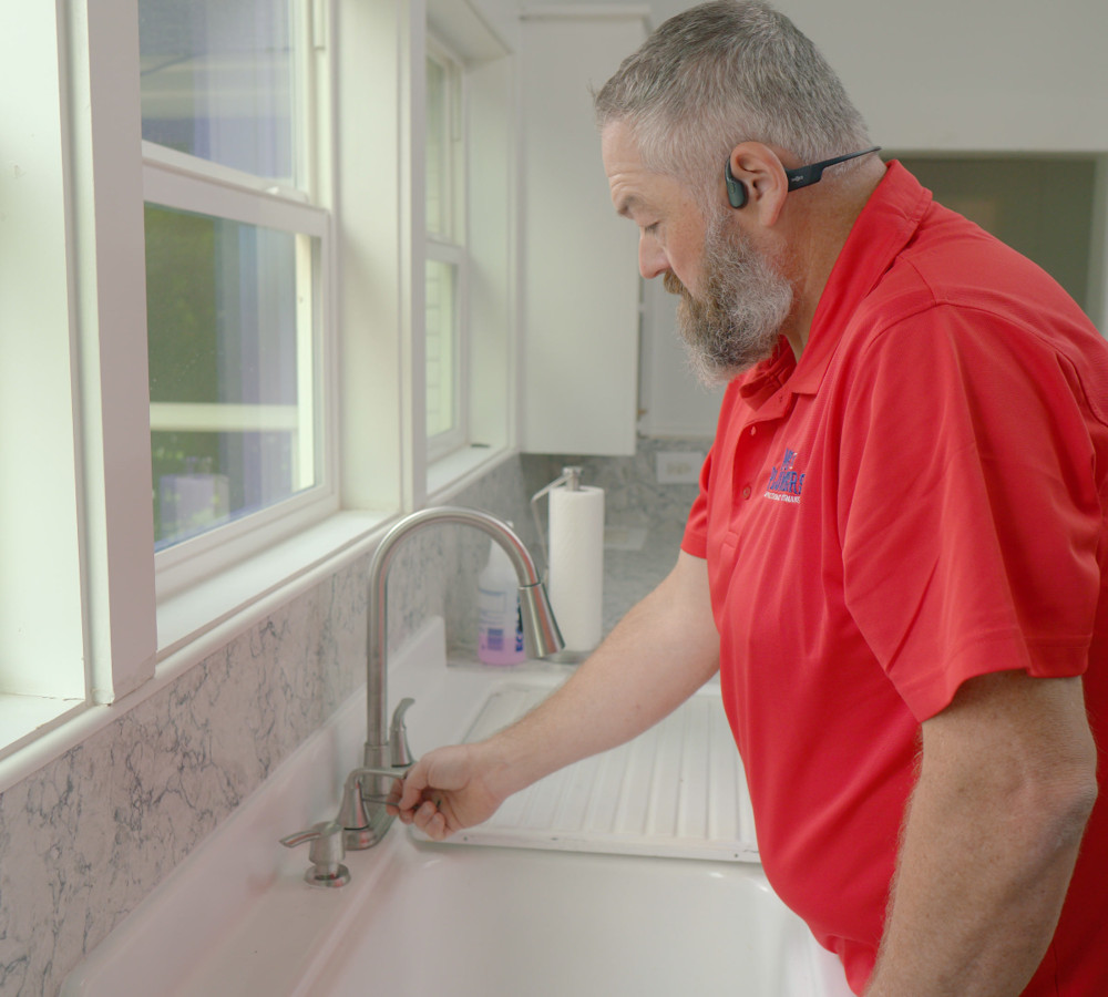 A plumber testing the water at a kitchen faucet
