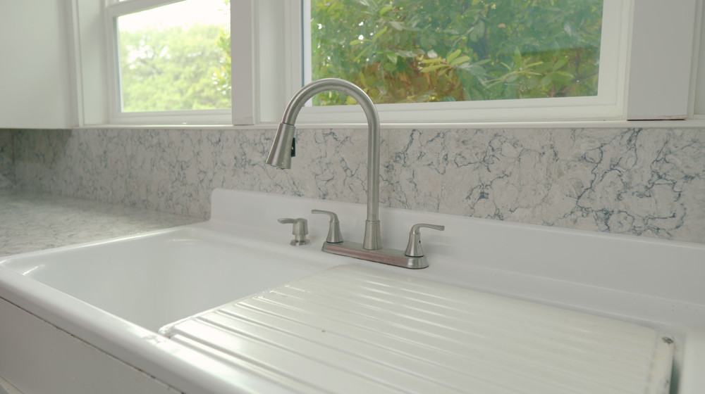 A kitchen faucet over a white farmhouse sink
