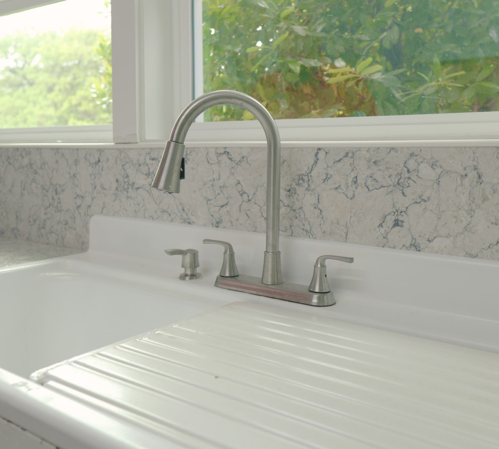 A kitchen faucet over a white farmhouse sink