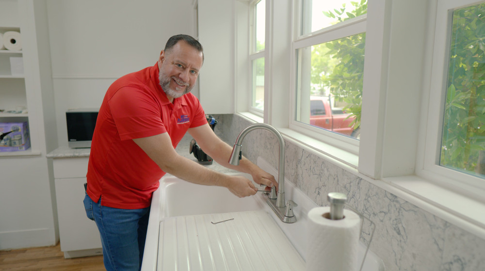 A plumber adjusting a new kitchen faucet