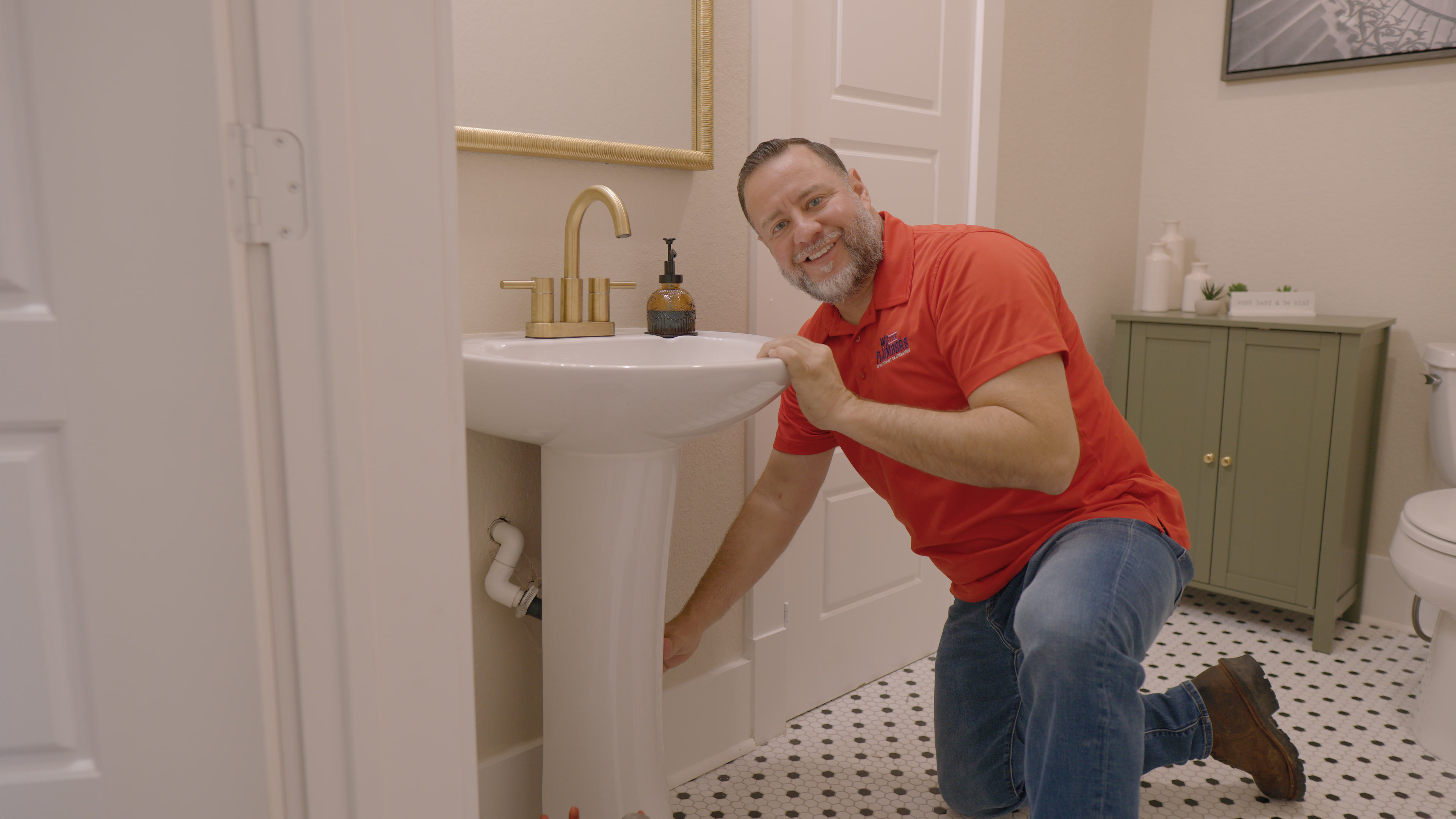 A We The Plumbers plumber smiling in a customer's bathroom
