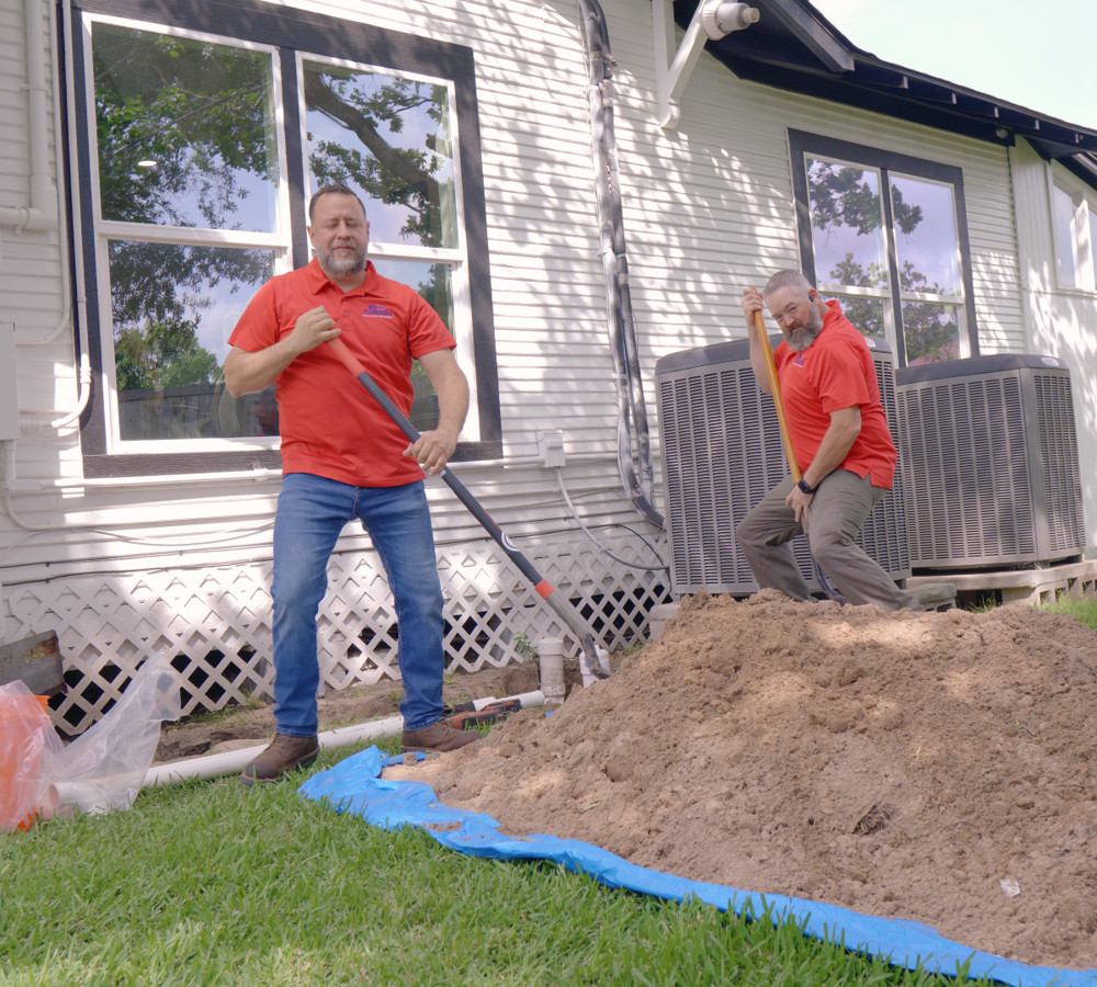 A plumber standing by a dug-out sewer line