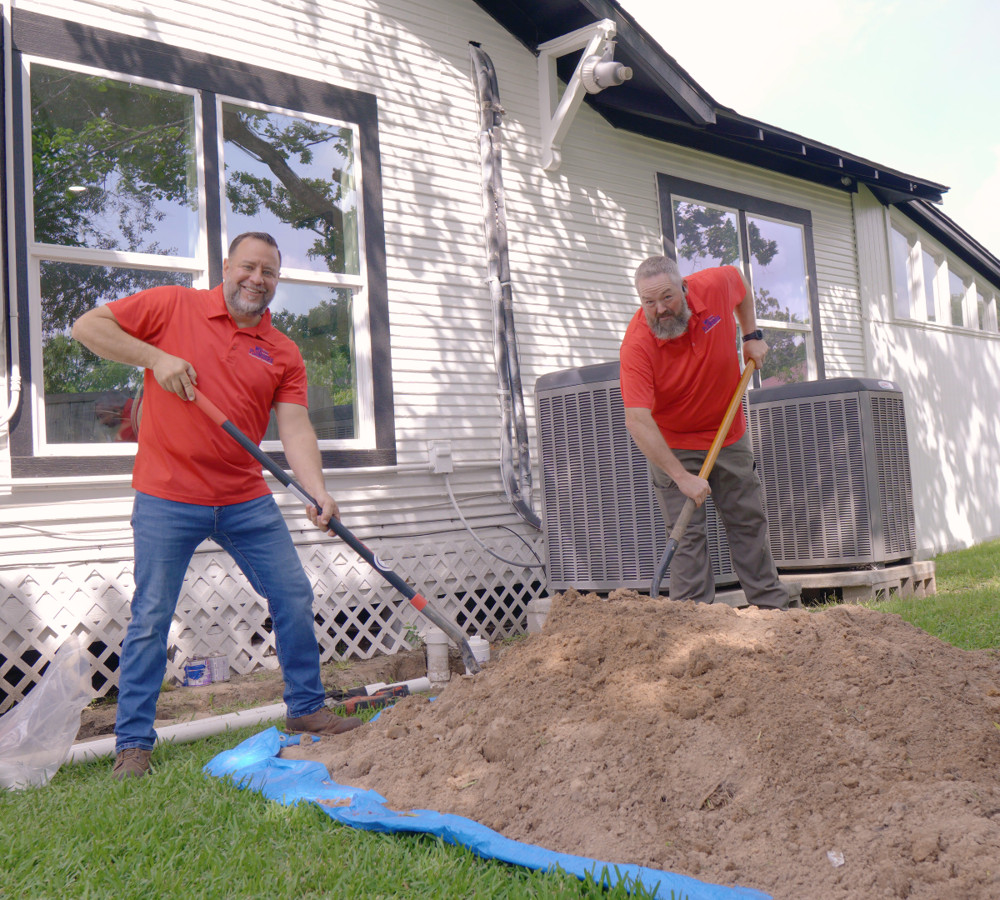 A plumber shoveling dirt at a sewer line excavation