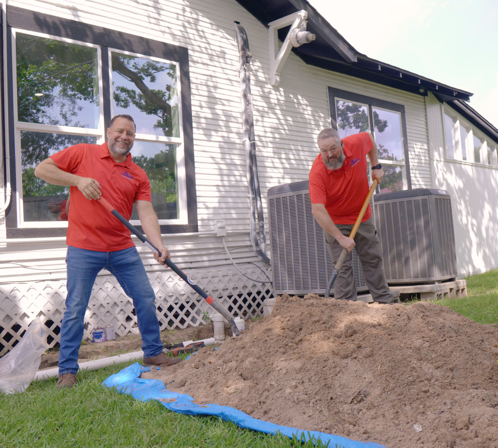 Plumbers excavating soil over a sewer line