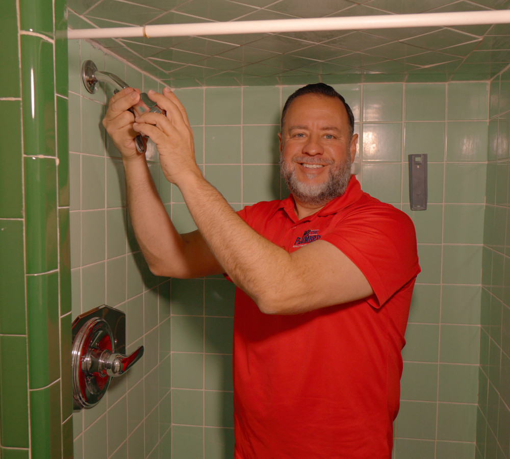 A plumber smiling while fixing a shower fixture