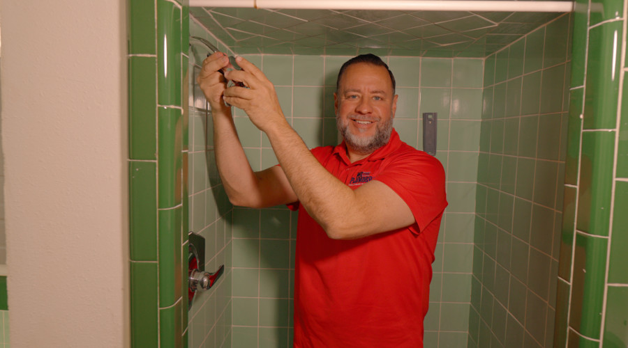 A plumber finishing work in a tiled shower