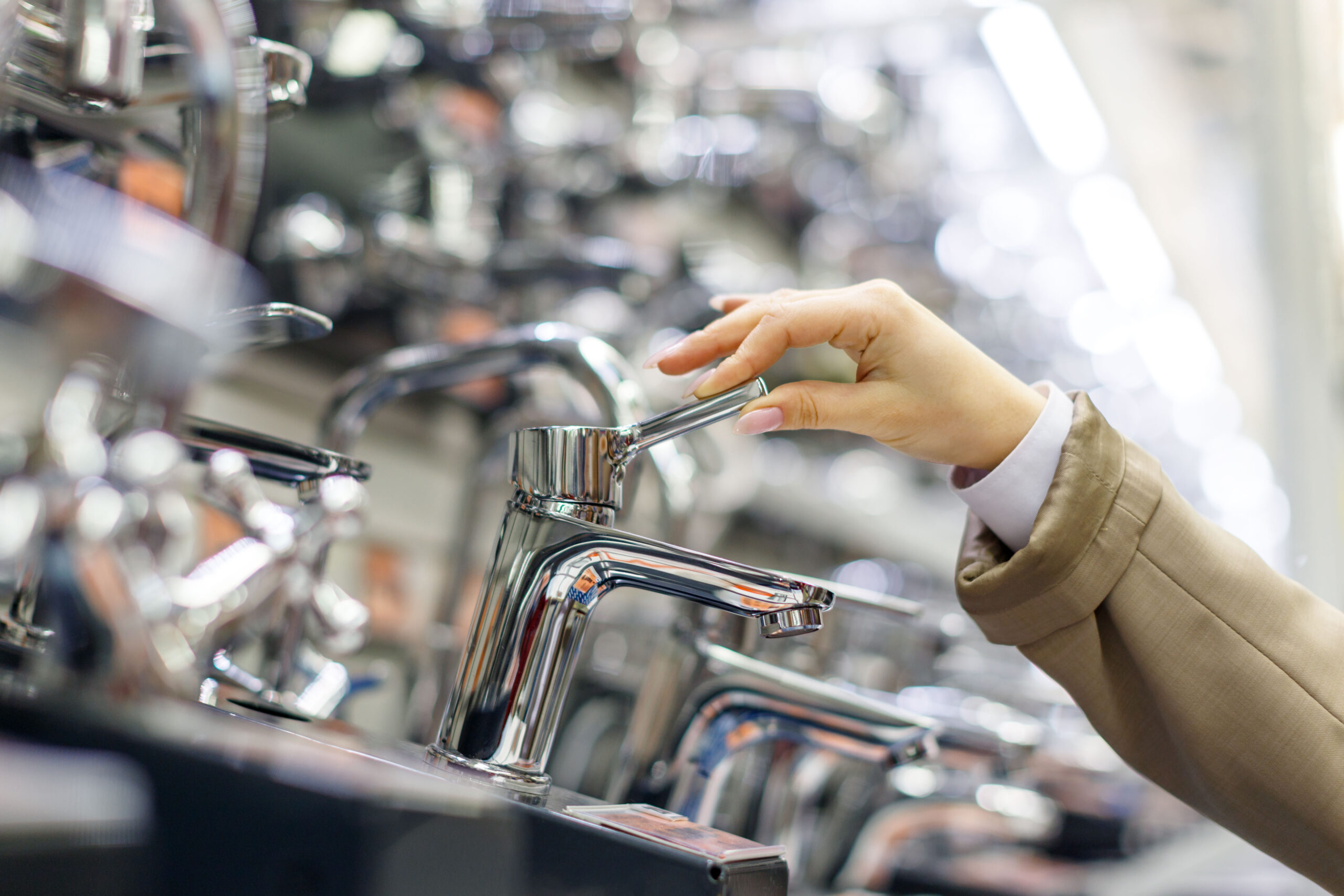 ustomer testing a new chrome faucet at a plumbing supply store while selecting fixtures for installation or replacement services in Conroe, Texas.